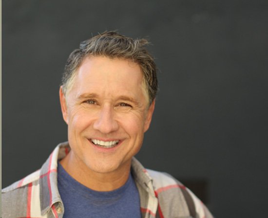 man smiling in front of a chalk board