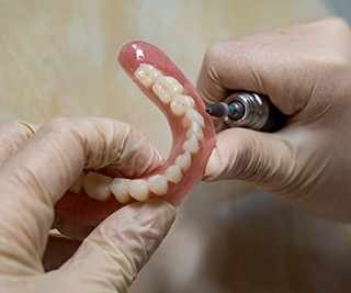 Lab technician filing dentures