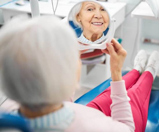 Dental patient looking at her teeth in mirror