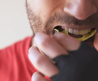 a man with dental implants putting on a mouthguard