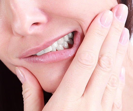 Closeup of person in pain holding jaw