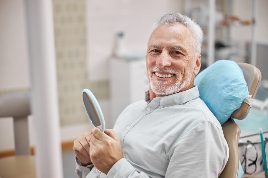 patient smiling in mirror after getting dental implants