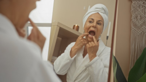 Woman examining her teeth in her bathroom mirror